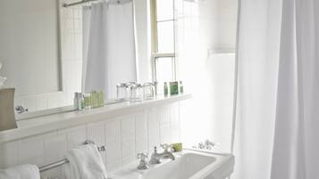 A bathroom with a white sink, a mirror, and a window with a curtain.