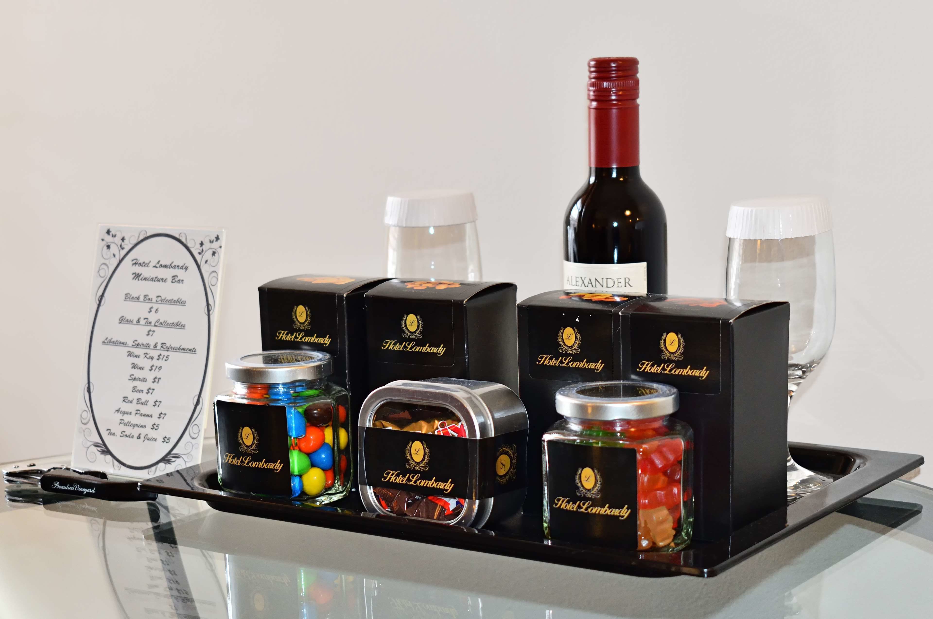 Un plateau contenant des articles de l’hôtel Lombardy, notamment une bouteille de vin Alexander, des pots de bonbons et un menu.