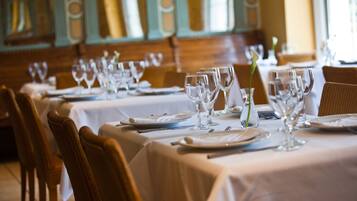 A dining area with tables set for service, chairs, and a decorative vase.