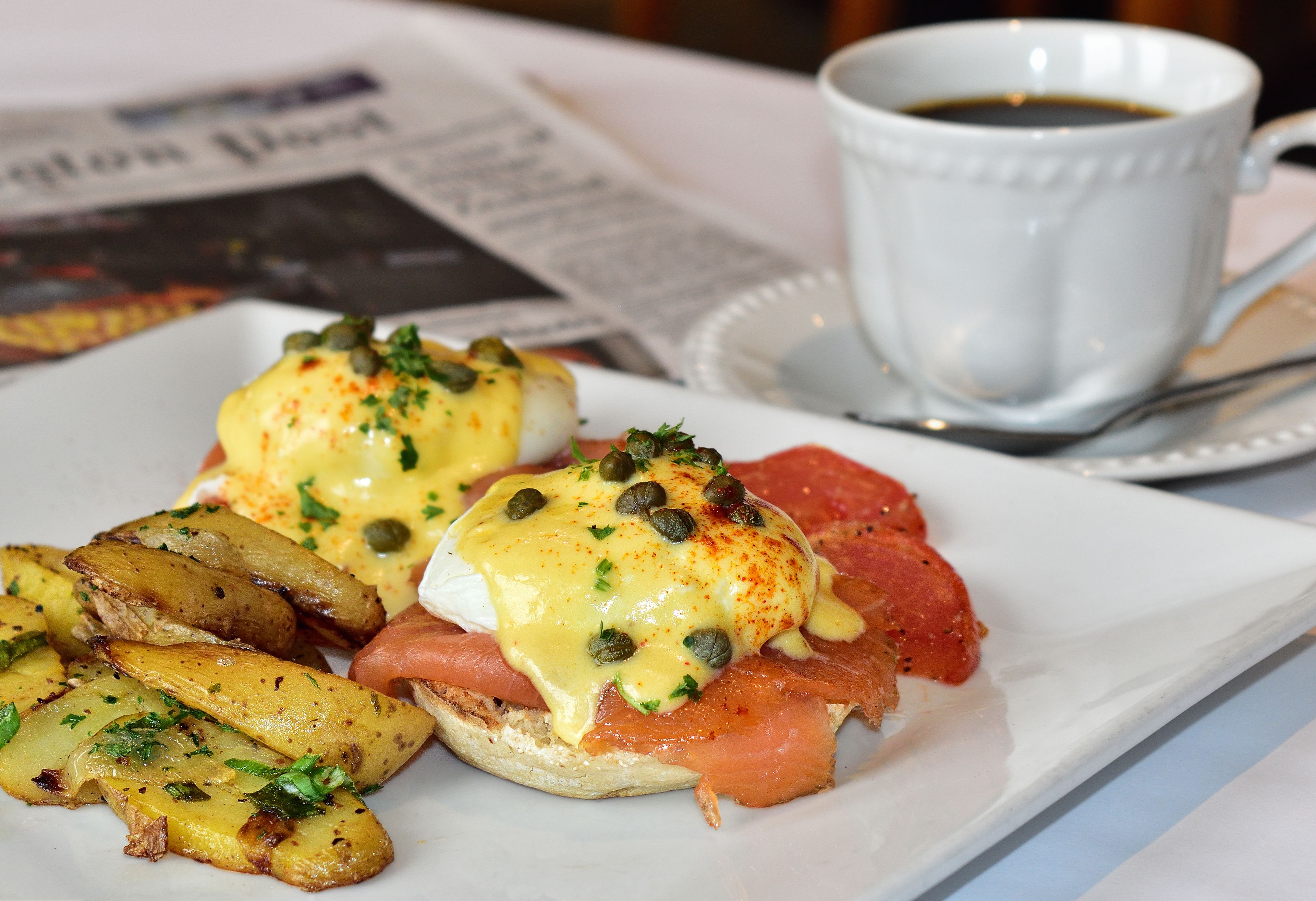 Une assiette de petit-déjeuner comprenant des œufs Bénédicte, du saumon fumé et des pommes de terre rôties.