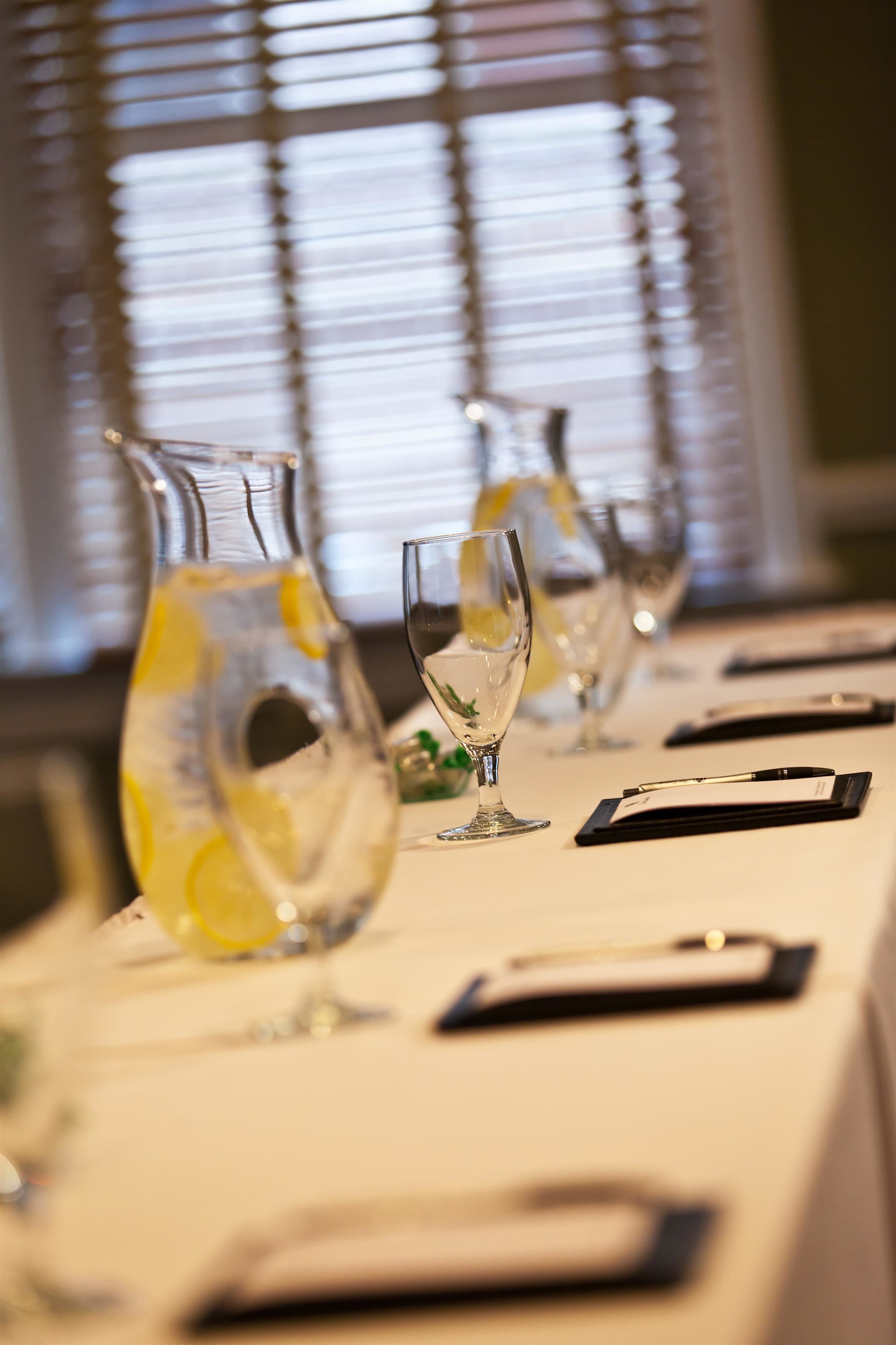 A table set with wine glasses, a pitcher, and a menu.