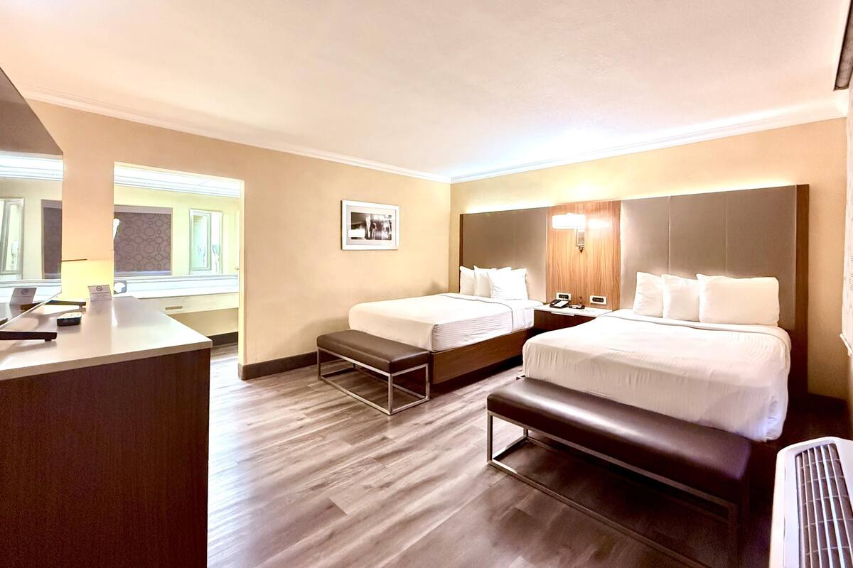 Ein Hotelzimmer mit zwei Betten, einem Schreibtisch und einer Bank.