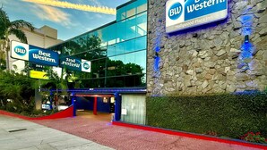 A Best Western hotel with a modern glass facade, a stone accent wall, and a clear sky with clouds. - Best Western Hollywood Plaza Hotel - Walk of Fame Film City LA (Los Angeles)