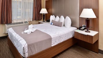 A hotel room with a large bed, two bedside tables, a wall-mounted air conditioner, and a window with curtains.