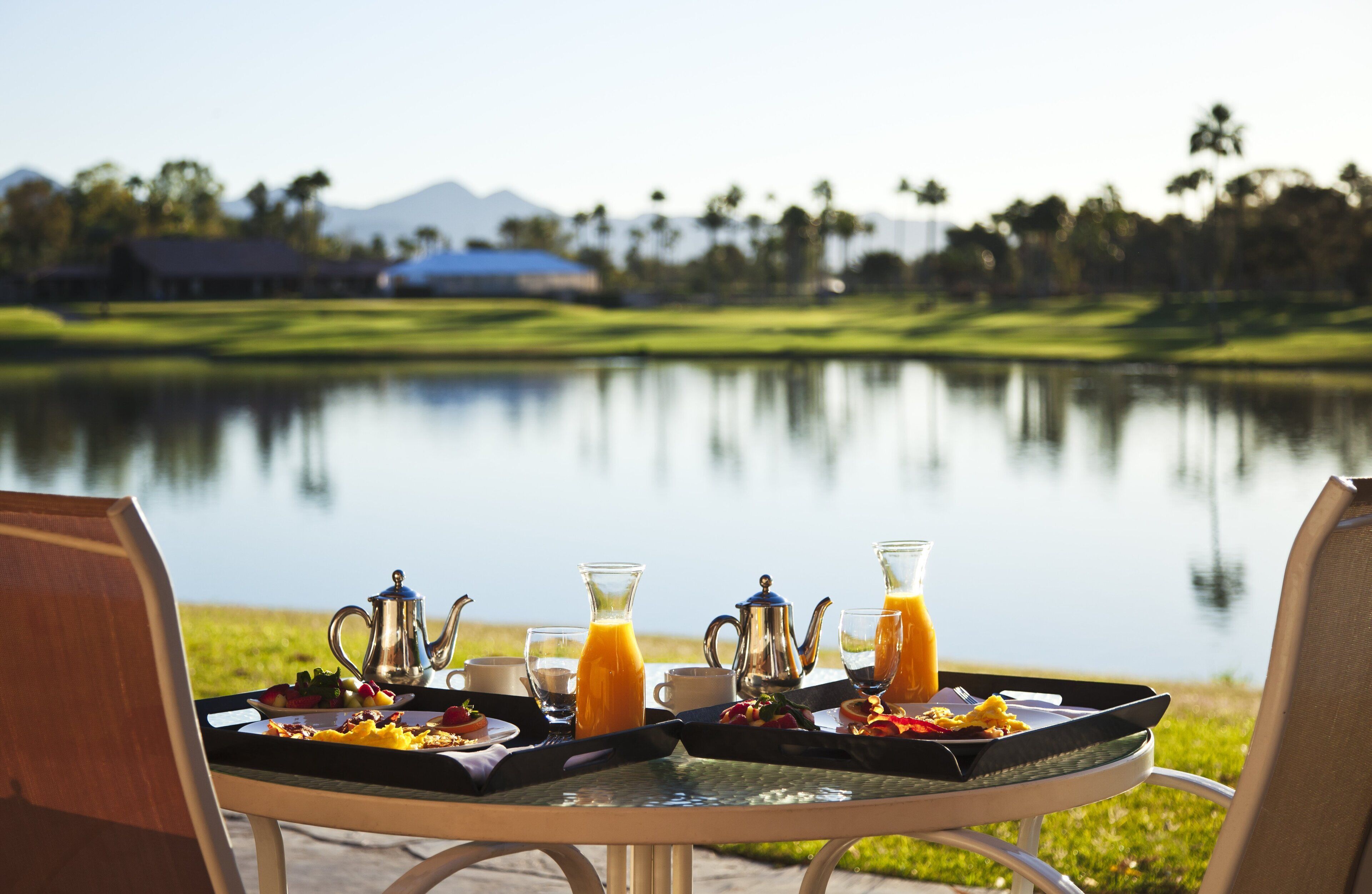 Una mesa con sillas dispuesta para el desayuno, con vistas a un lago y un campo de golf.