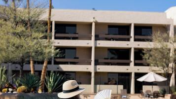 A person sitting by a pool with a building in the background.