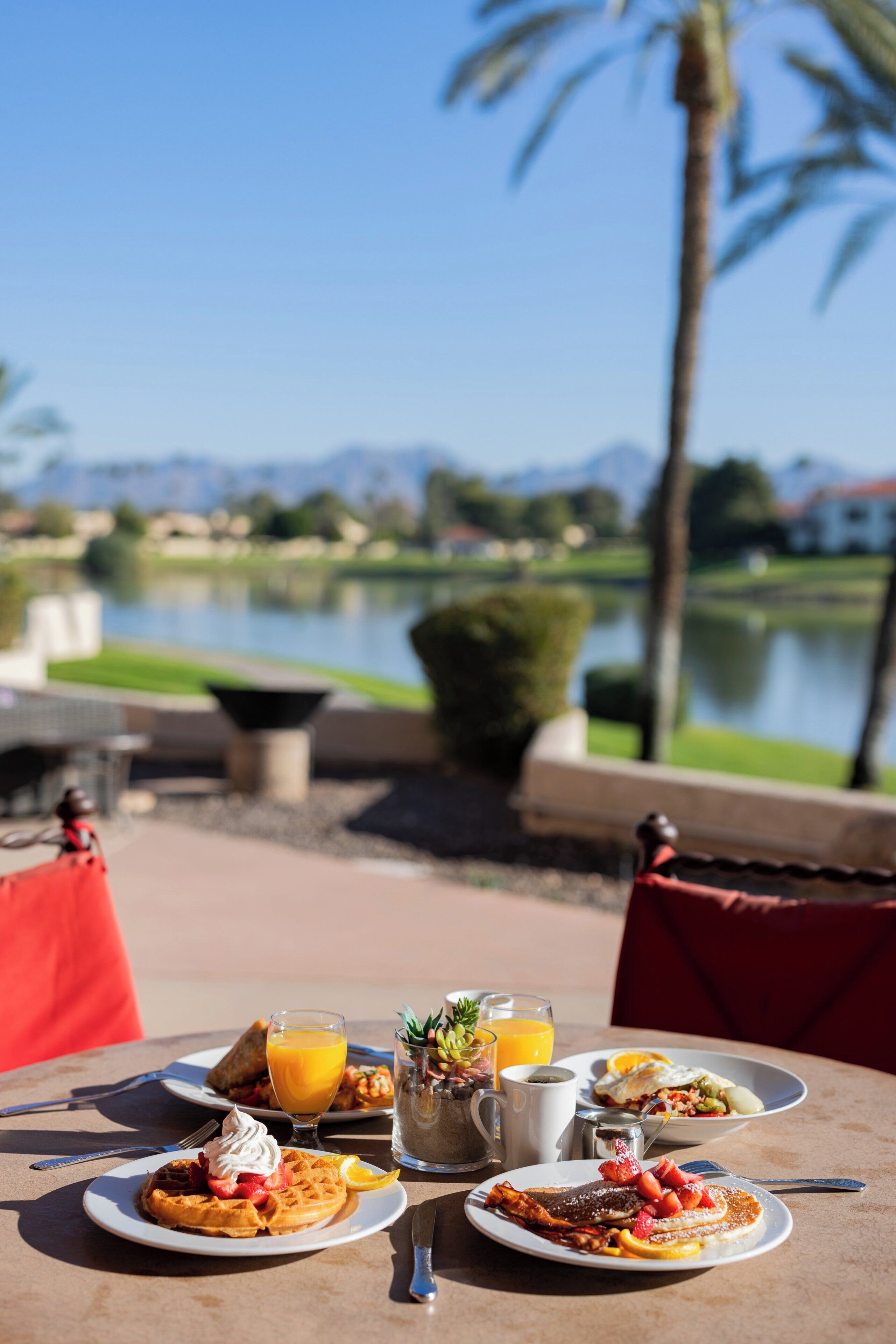 A dining table with breakfast plates, a pitcher, and a glass of orange juice.