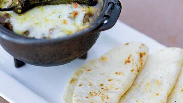 A white plate with a black bowl containing a soup and flatbread.