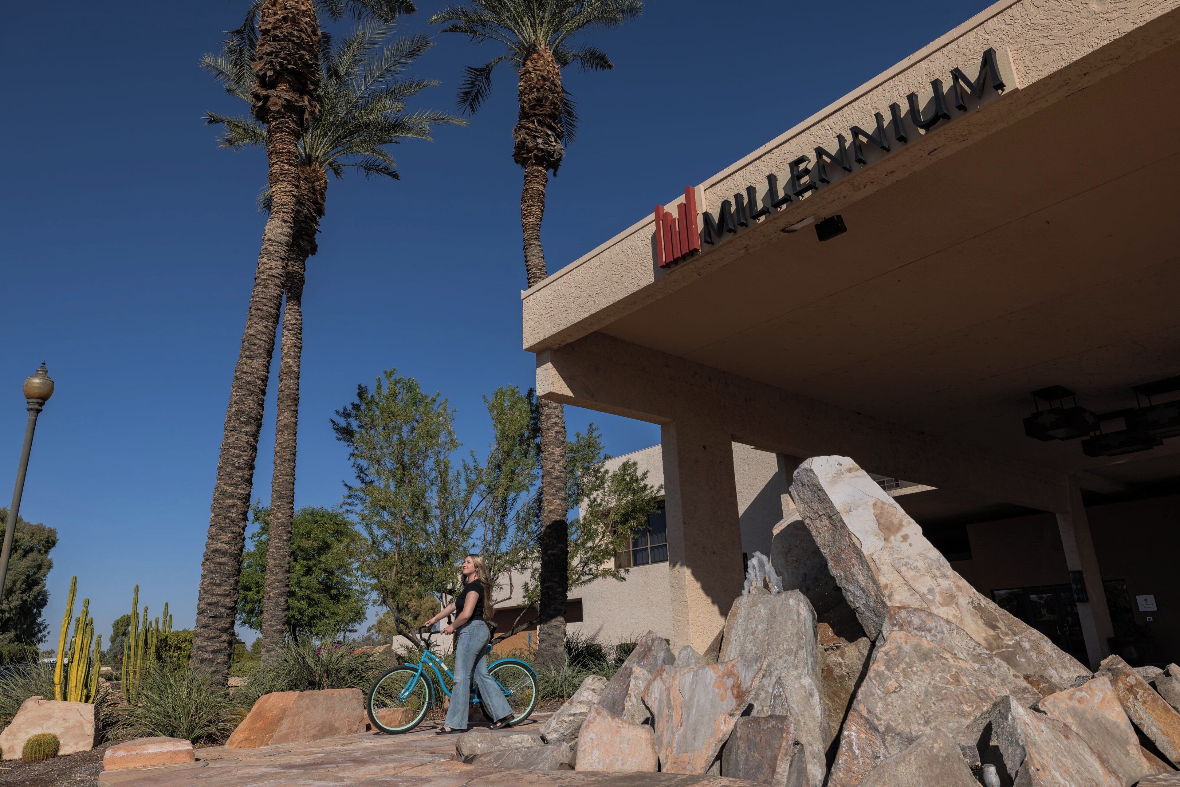 A building with a sign reading 'MILLENNIUM' and a person riding a bicycle.