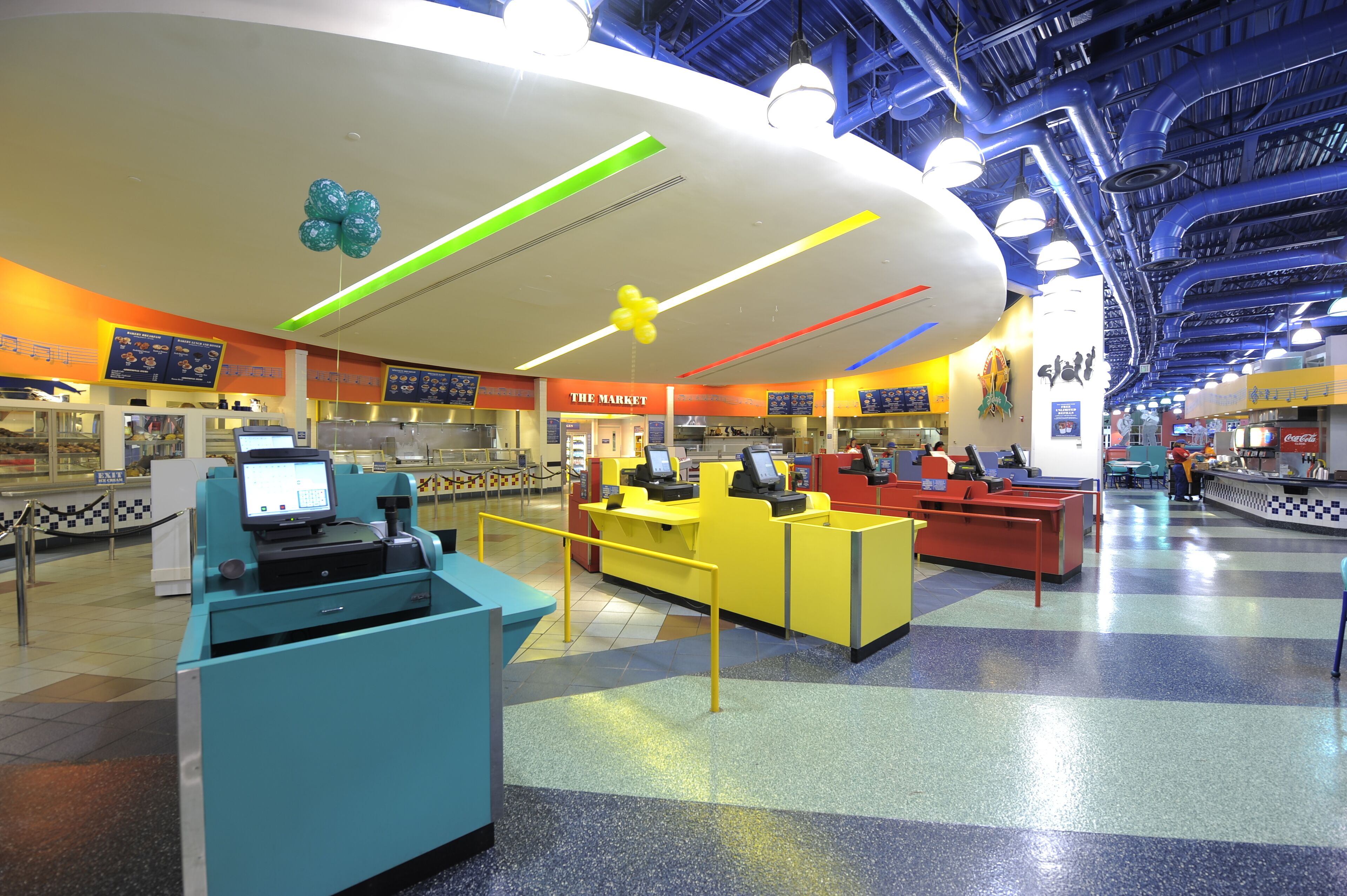 A brightly lit indoor space with multiple service counters, a central kiosk, and a check-in area.