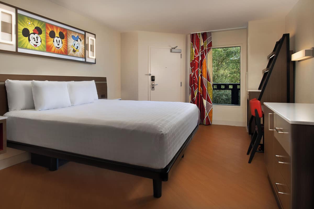 A hotel room with a bed, bedside table, and a window with curtains.