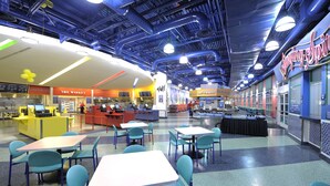 A cafeteria with tables and chairs, a vending machine, and a counter with a menu. - Disney's All-Star Music Resort (Lake Buena Vista)
