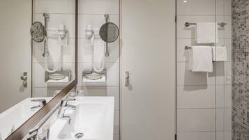 Une salle de bain moderne avec un grand miroir, un lavabo, une douche et des toilettes.
