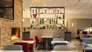 Moderni ravintola, jossa on tiiliseinä, baarialue pulloineen sekä pöytiä ja tuoleja sisältävä ruokailutila.