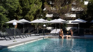 Una piscina al aire libre de temporada, sombrillas