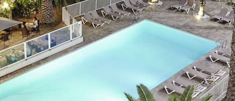 En säsongsöppen utomhuspool, parasoller och solstolar