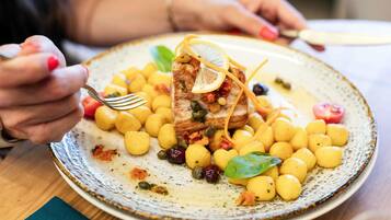 Ein Teller mit Fischfilet, Zitrone, Kapern und dazu gelbe Pasta.