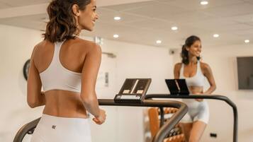 Una palestra con tapis roulant, uno specchio a parete e un portatile su una delle macchine.