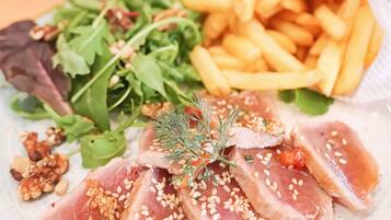 Um prato com carne fatiada, batatas fritas e vegetais.
