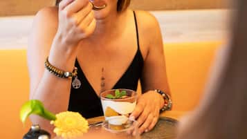 A person sitting at a table with a drink and a flower.