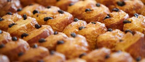 A close-up of a baked good with a golden-brown crust and dark specks, likely chocolate chips.