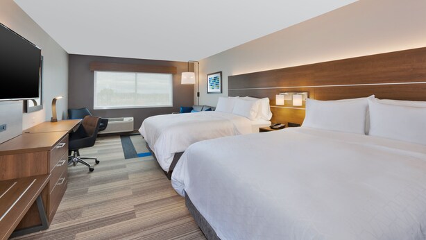 Een hotelkamer met twee bedden, een bureau, een televisie en een raam met uitzicht.