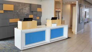 Een receptiebalie met een modern ontwerp, met een grijze en houten wandpaneel en een blauw accentpaneel.