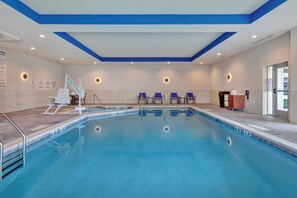 A swimming pool with a diving board, lounge chairs, and a changing area.