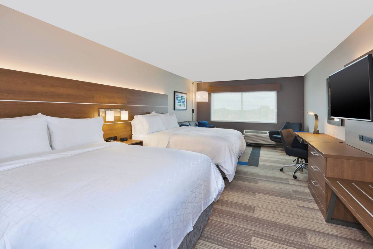 Een hotelkamer met twee bedden, een bureau, een televisie en een raam met uitzicht.