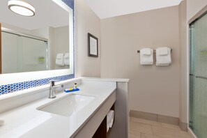 Een moderne badkamer met een grote spiegel, twee wasbakken en een douche.