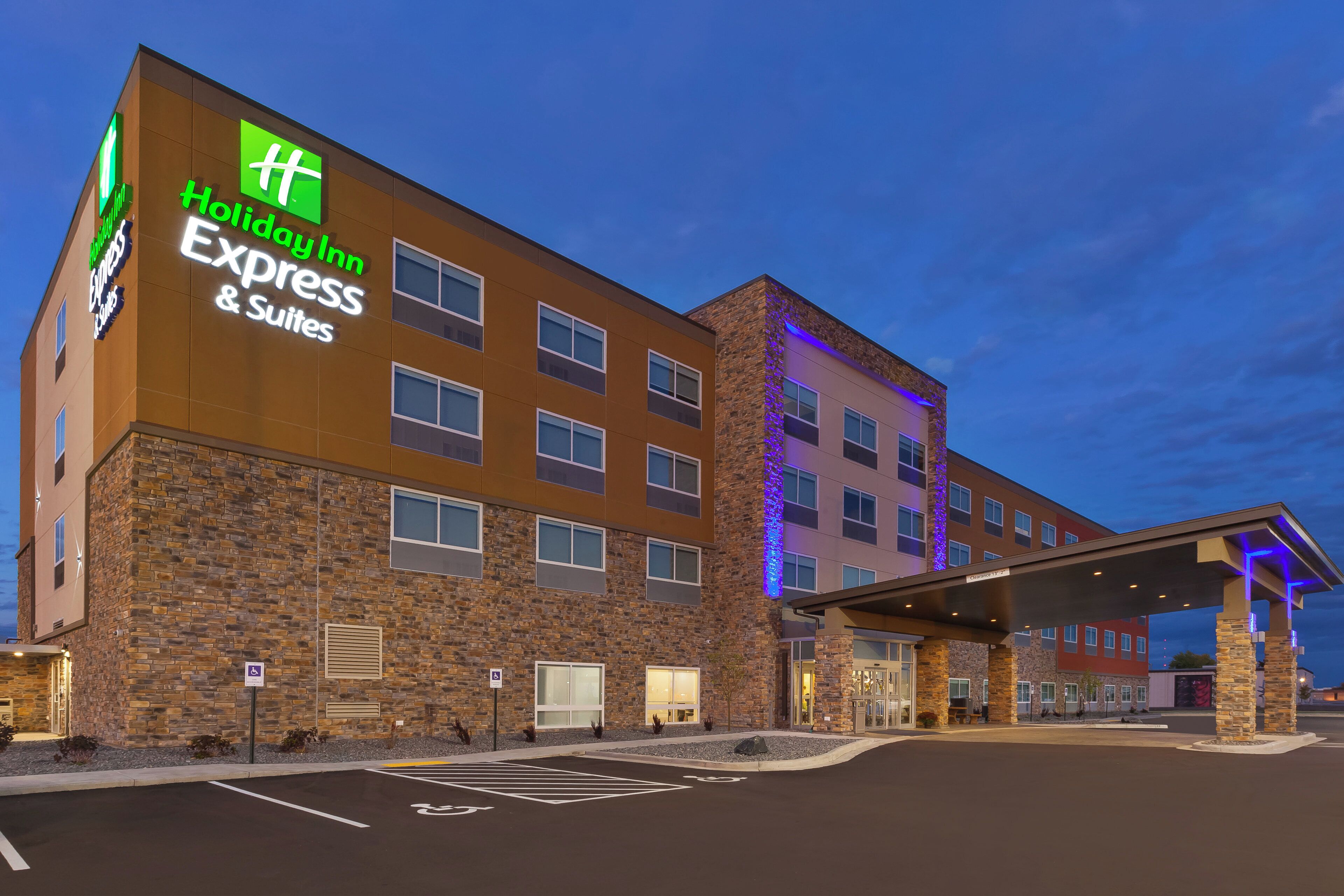 A Holiday Inn Express & Suites building with a stone facade, multiple windows, and a covered entrance area.