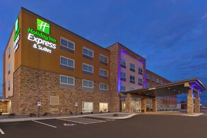 Edificio de Holiday Inn Express & Suites con fachada de piedra, múltiples ventanas y un área de entrada cubierta.
