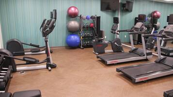 A gym with treadmills, elliptical machines, and various exercise balls.