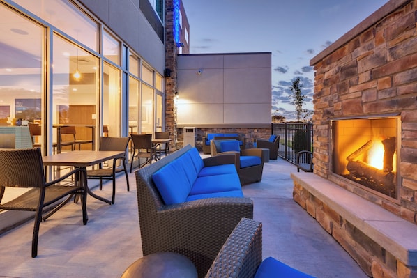 An outdoor seating area with wicker furniture and a stone wall.