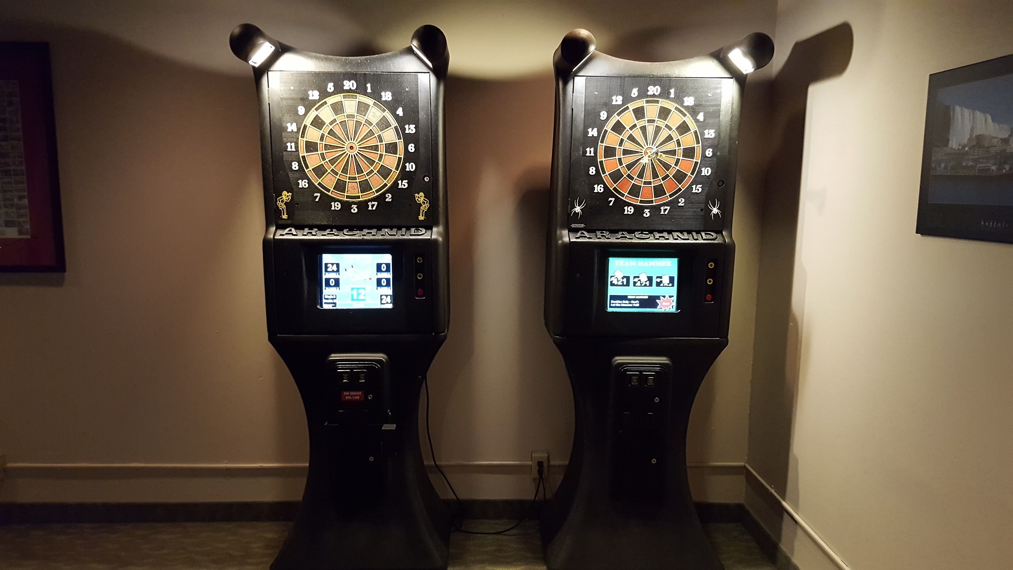 Two dartboards mounted on stands in a hallway.