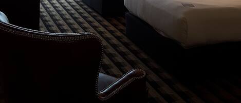 Habitación de hotel con dos camas, un escritorio, una silla y un ventanal con cortinas.