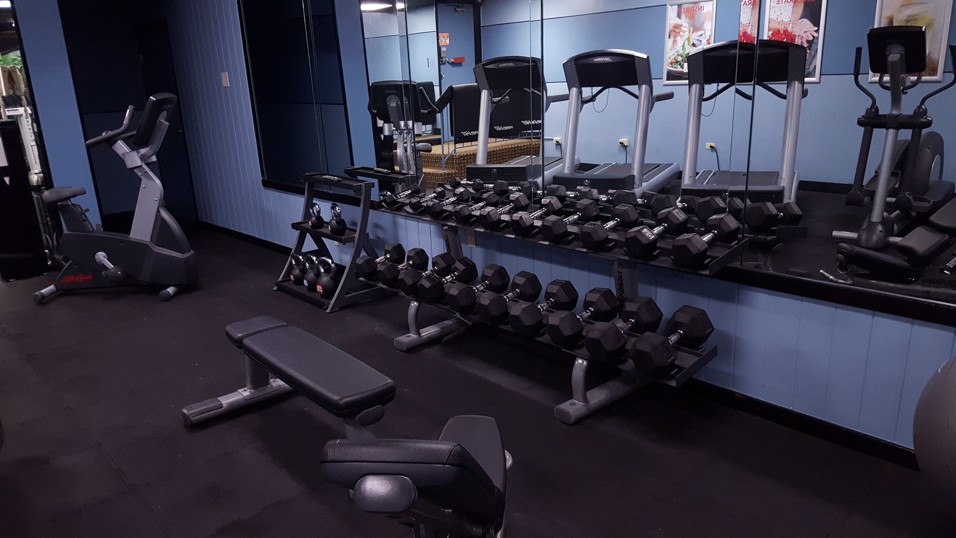 A gym with exercise equipment, including treadmills, dumbbells, and weight benches.