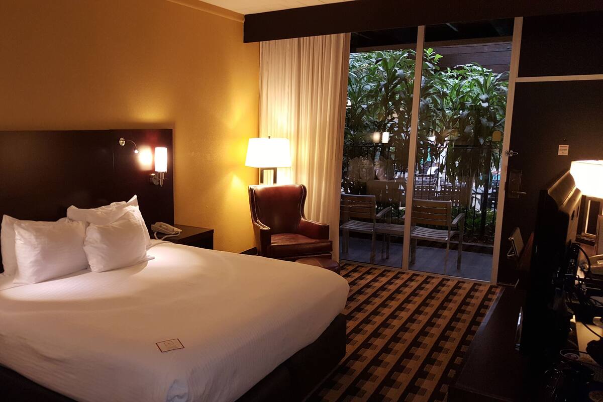 Un cuarto de hotel con una cama grande, una silla, un escritorio y vista al exterior.