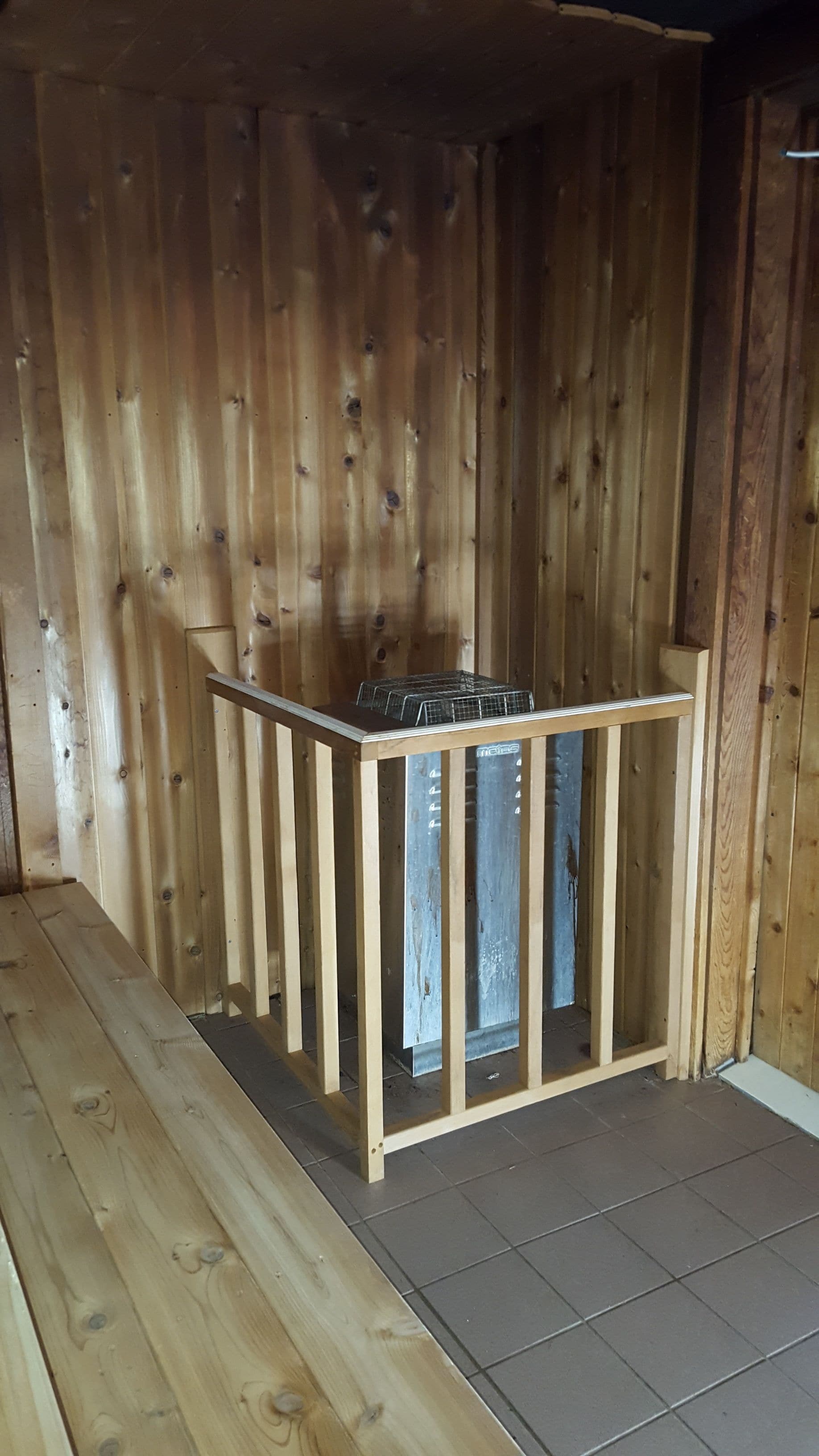 A wooden room with a built-in bench and a metal rack.