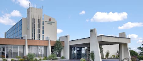 A modern hotel with a prominent entrance, large windows, and a well-maintained lawn.