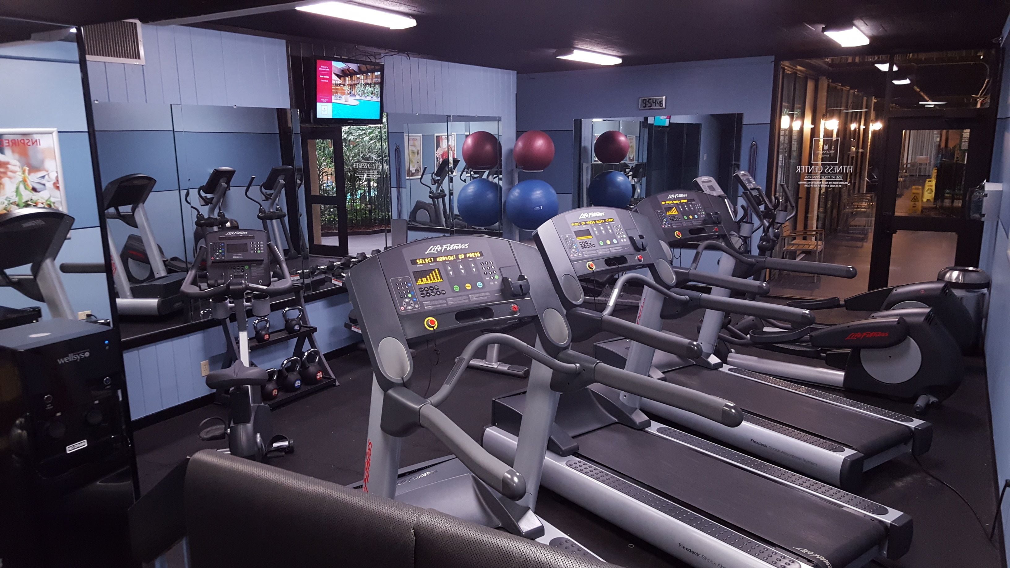 Un gimnasio con cintas de correr, pesas y pelotas de ejercicio.