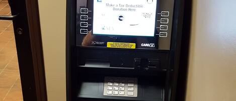 An ATM machine with a screen displaying a message about making a tax-deductible donation.