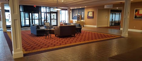 A spacious lobby with a patterned carpet, seating area with sofas and armchairs, and a sign indicating ballrooms.