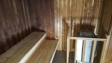A wooden cabin interior with a bench and a metal rack.