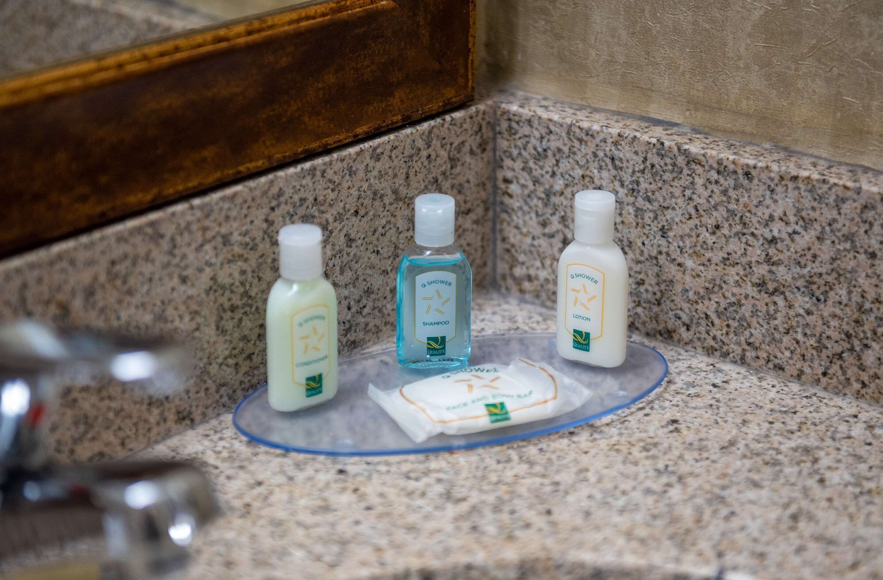 En badrumsbänk med tre hygienprodukter: en flaska med lotion, en flaska schampo och en tvål.