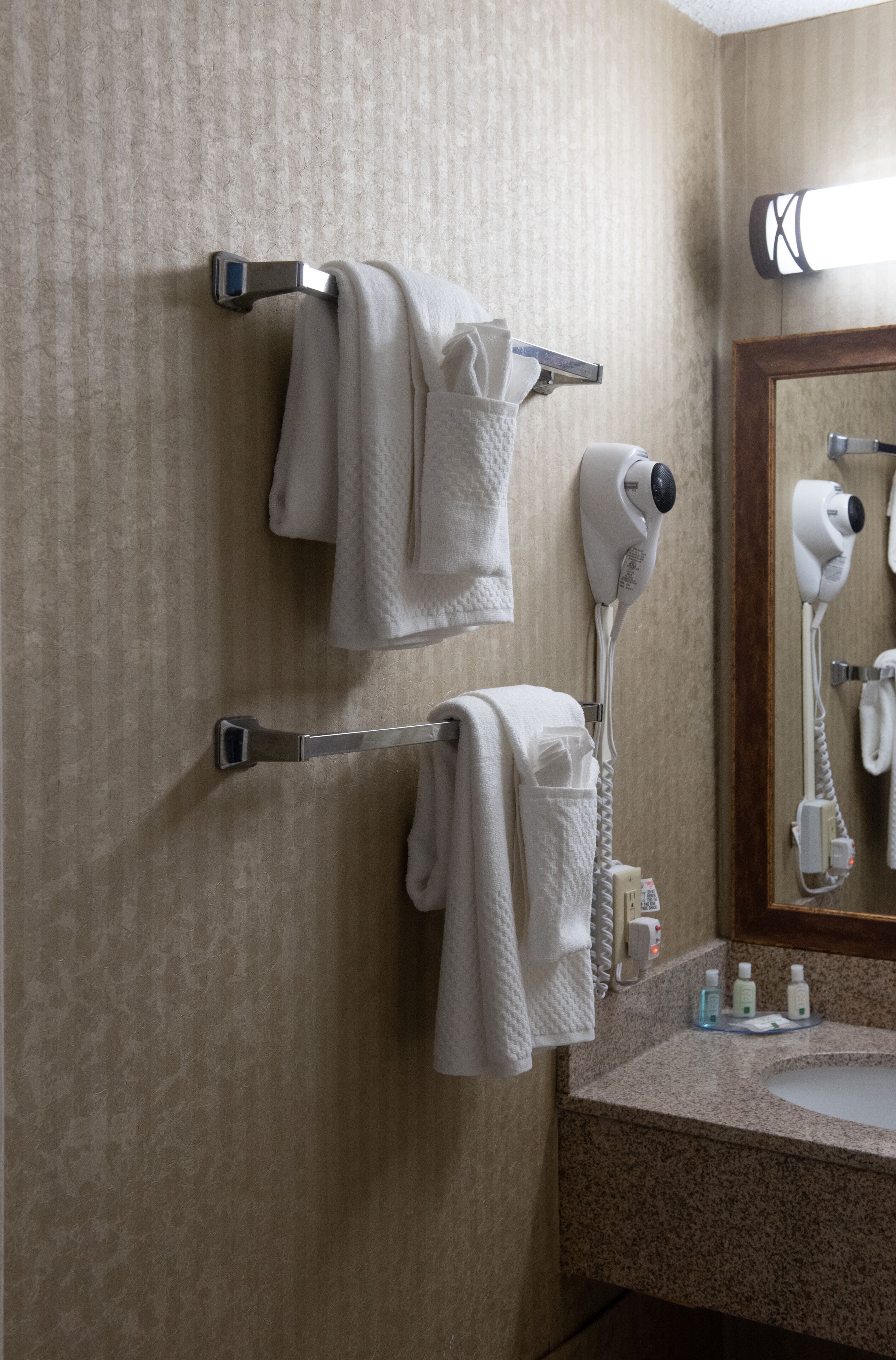 Un baño con toallero, secador de pelo y espejo.
