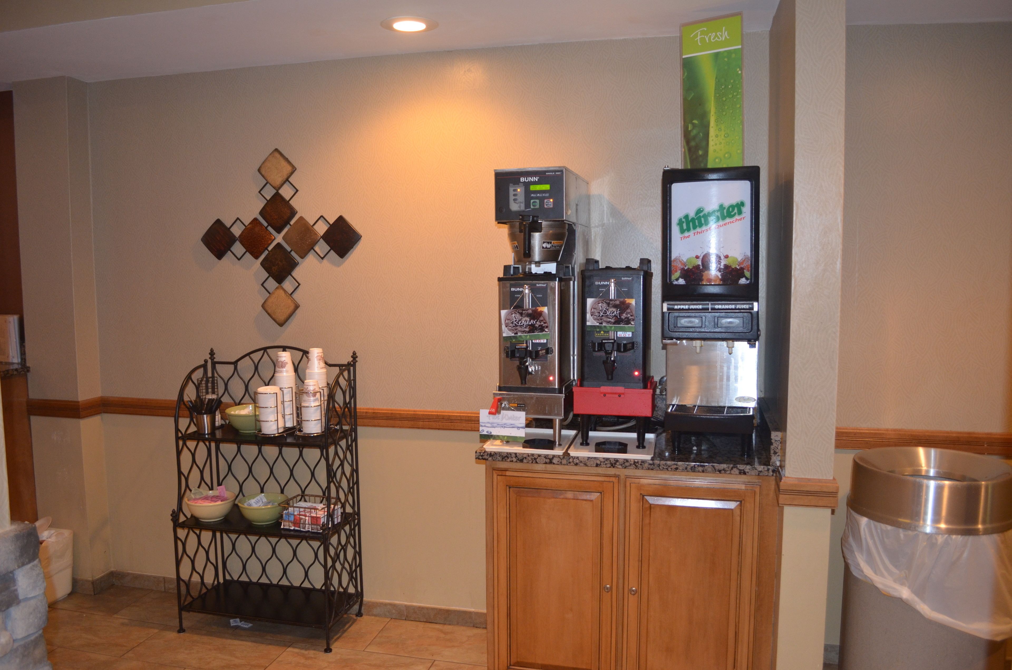 A kitchenette with a coffee machine, a refrigerator, and a shelf with kitchenware.