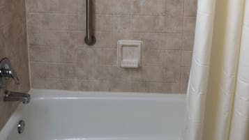 Baño con bañera, ducha y barras de apoyo.
