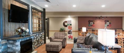 A spacious living area with a stone fireplace, comfortable seating, a flat-screen TV, and a decorative wall.