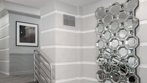 En modern inredning med en trappa, en grön bänk och en vägg med en geometrisk spegeldesign.